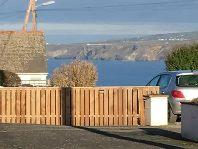 a wooden fence with a view of a body of water at Puffins in Port Isaac