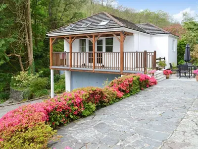 a house with a gazebo with pink flowers at River Lodge in Polperro