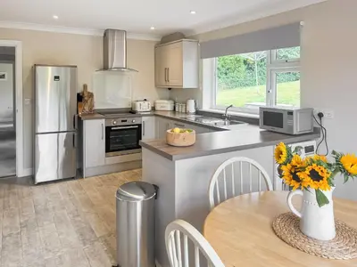a kitchen with a table and a refrigerator at Silvershell View in Port Isaac