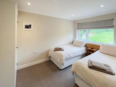 two beds in a room with a window at Silvershell View in Port Isaac