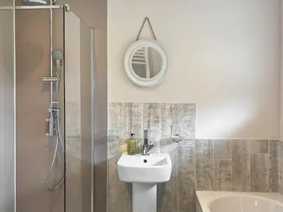 a bathroom with a sink and a shower with a mirror at Silvershell View in Port Isaac