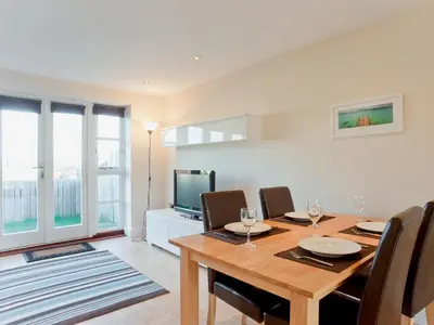 a dining room with a table and chairs and a television at Bay Retreat Villas in St Merryn