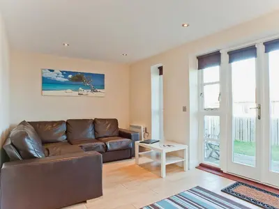 a living room with a leather couch and a table at Bay Retreat Villas in St Merryn