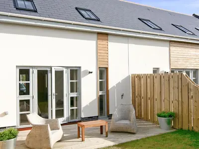 a white house with chairs and a table at Bay Retreat Villas in St Merryn