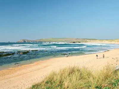 a beach with people walking on the sand and the ocean at Bay Retreat Villas in St Merryn