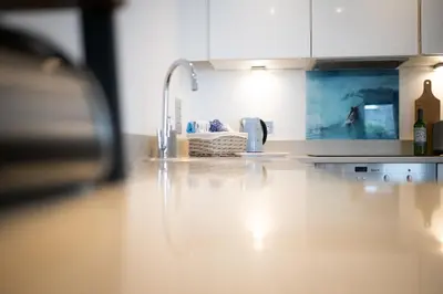 a kitchen with white cabinets and a counter top at Seaview, Luxury apartment, 2 min walk to Porth Beach in Newquay