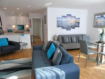 a living room with a couch and a table at Seaview, Luxury apartment, 2 min walk to Porth Beach in Newquay