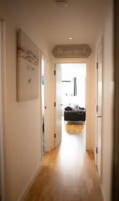 a hallway with a room with a couch and a sign that reads be our guest at Seaview, Luxury apartment, 2 min walk to Porth Beach in Newquay