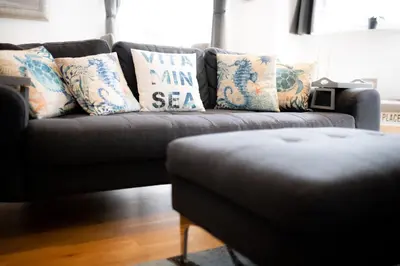 a couch with pillows on it in a living room at Seaview, Luxury apartment, 2 min walk to Porth Beach in Newquay