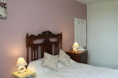 a bedroom with a bed with white sheets and two lamps at Trevanger Farm Bed and Breakfast in Wadebridge