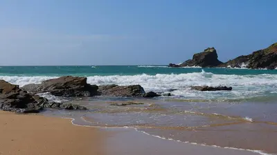a beach with rocks and the ocean with waves at Caroe Farm House in Otterham