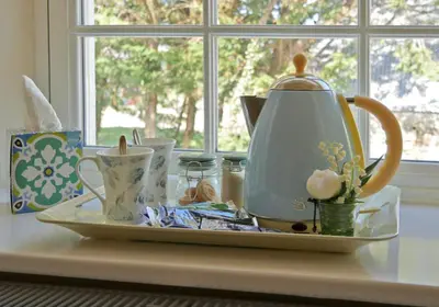 a plate with a tea kettle on a table next to a window at Caroe Farm House in Otterham