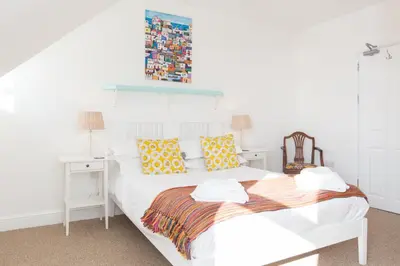 a white bedroom with a white bed with yellow pillows at 3 Porthminster B&B in St Ives
