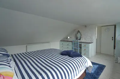 a bedroom with a striped bed and a dresser at The Old Coach House in Boscastle