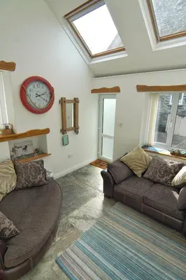 a living room with a couch and a clock on the wall at The Old Coach House in Boscastle