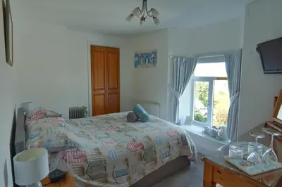 a bedroom with a bed and a window at The Old Coach House in Boscastle