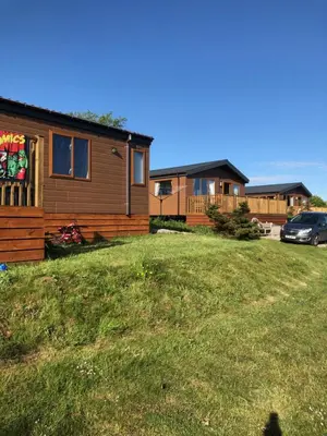 a log cabin with a car parked in a yard at Clearwater lodge in Perranporth