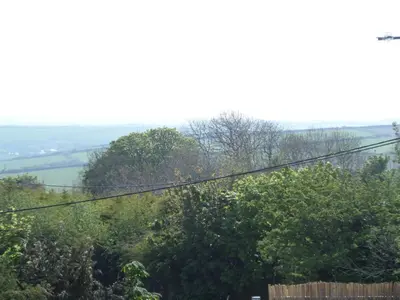 a view of a hill with trees and power lines at Clearwater lodge in Perranporth