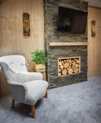 a living room with a fireplace with a tv and a chair at Rockleigh Place in St Austell