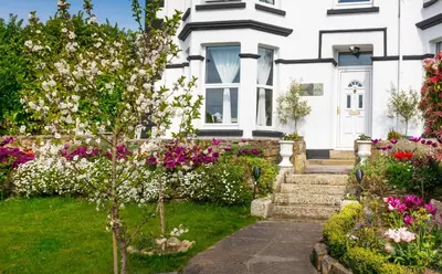 a white house with flowers in the front yard at Rockleigh Place in St Austell