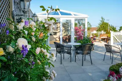 a patio with a table and chairs and flowers at Rockleigh Place in St Austell