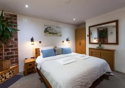a bedroom with a large bed and a mirror at Rockleigh Place in St Austell