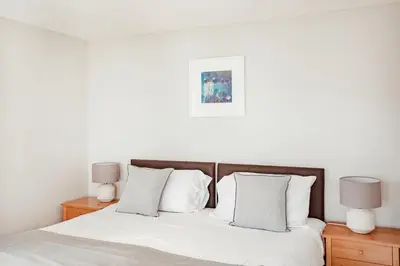 a bedroom with a bed with white sheets and two lamps at The Bay Hotel in Coverack