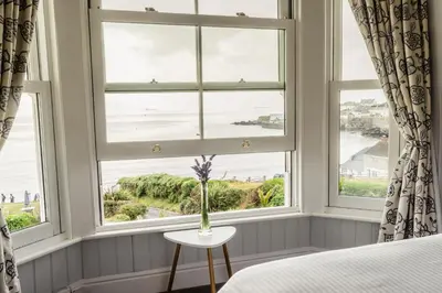 a bedroom with a window with a view of the ocean at The Bay Hotel in Coverack