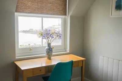 a vase of flowers on a wooden table in front of a window at The Bay Hotel in Coverack