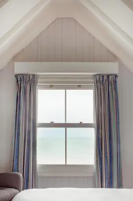 a bedroom with a window with a view of the ocean at The Bay Hotel in Coverack