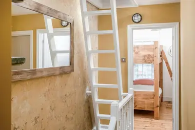 a room with a ladder and a mirror and a bunk bed at The Bunker House in Newquay