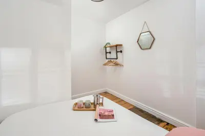 a room with white walls and a table with a shelf at The Bunker House in Newquay