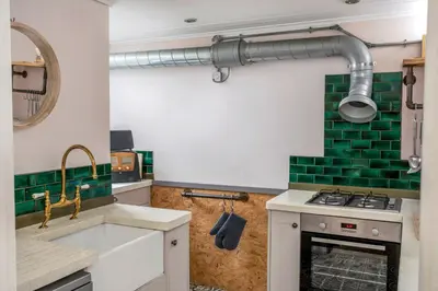 a kitchen with a sink and a stove with green tiles at The Bunker House in Newquay