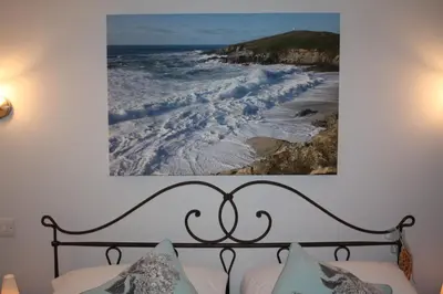 a picture hanging above a bed with the ocean at Linton Luxury Holiday Home in Mevagissey