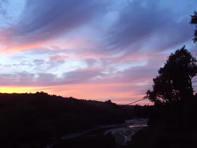 a sunset over a river with trees in the foreground at Woodlands in Looe