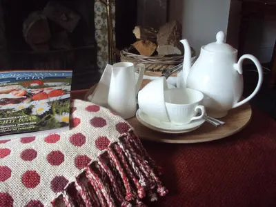 a table with a plate with a tea set and a book at Woodlands in Looe