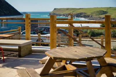 a wooden deck with a bench and a view of the beach at Oystercatcher Apartments in Polzeath