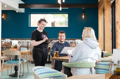 a woman standing in a restaurant with a man at Oystercatcher Apartments in Polzeath