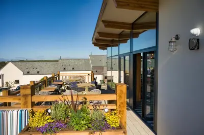 a balcony with a patio with tables and chairs at Oystercatcher Apartments in Polzeath