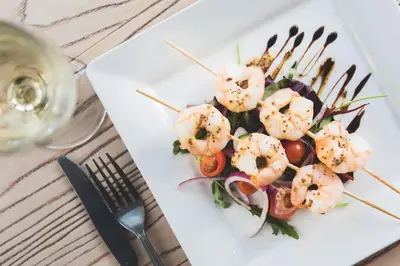 a plate of shrimp salad with a glass of wine at Oystercatcher Apartments in Polzeath