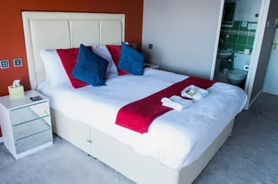a bedroom with a large white bed with red and blue pillows at Poltair Guest House in Falmouth