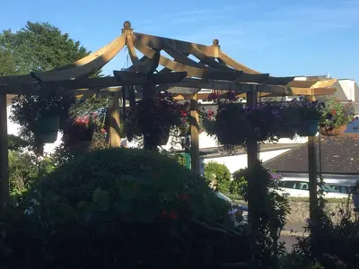 a wooden pergola with potted plants and flowers at Poltair Guest House in Falmouth
