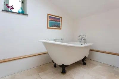 a white bath tub in a bathroom with a picture on the wall at The Snuggery in Truro