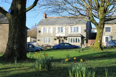 a large stone house with cars parked in front of it at Tom in Bodmin