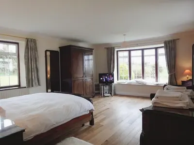 a bedroom with a bed and a tv and windows at Higher Tumrose in Blisland
