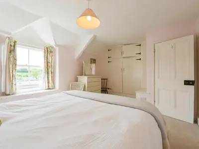 a white bedroom with a bed and a window at Agar Cottage in Port Isaac