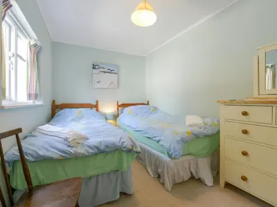 two twin beds in a room with a dresser at Agar Cottage in Port Isaac
