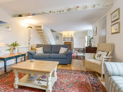 a living room with a blue couch and a table at Agar Cottage in Port Isaac