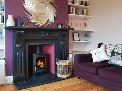 a living room with a fireplace and a couch at Heightley House in Tintagel
