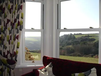 a living room with two windows and a couch at Heightley House in Tintagel